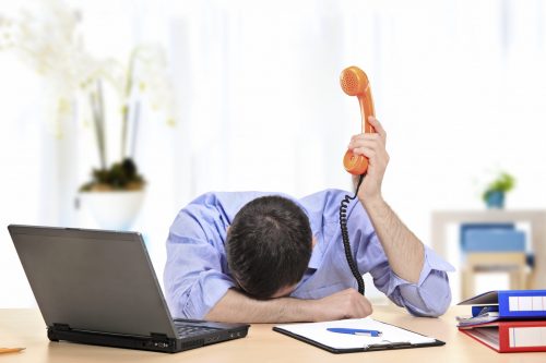 Exhausted businessman holding a telephone in his office